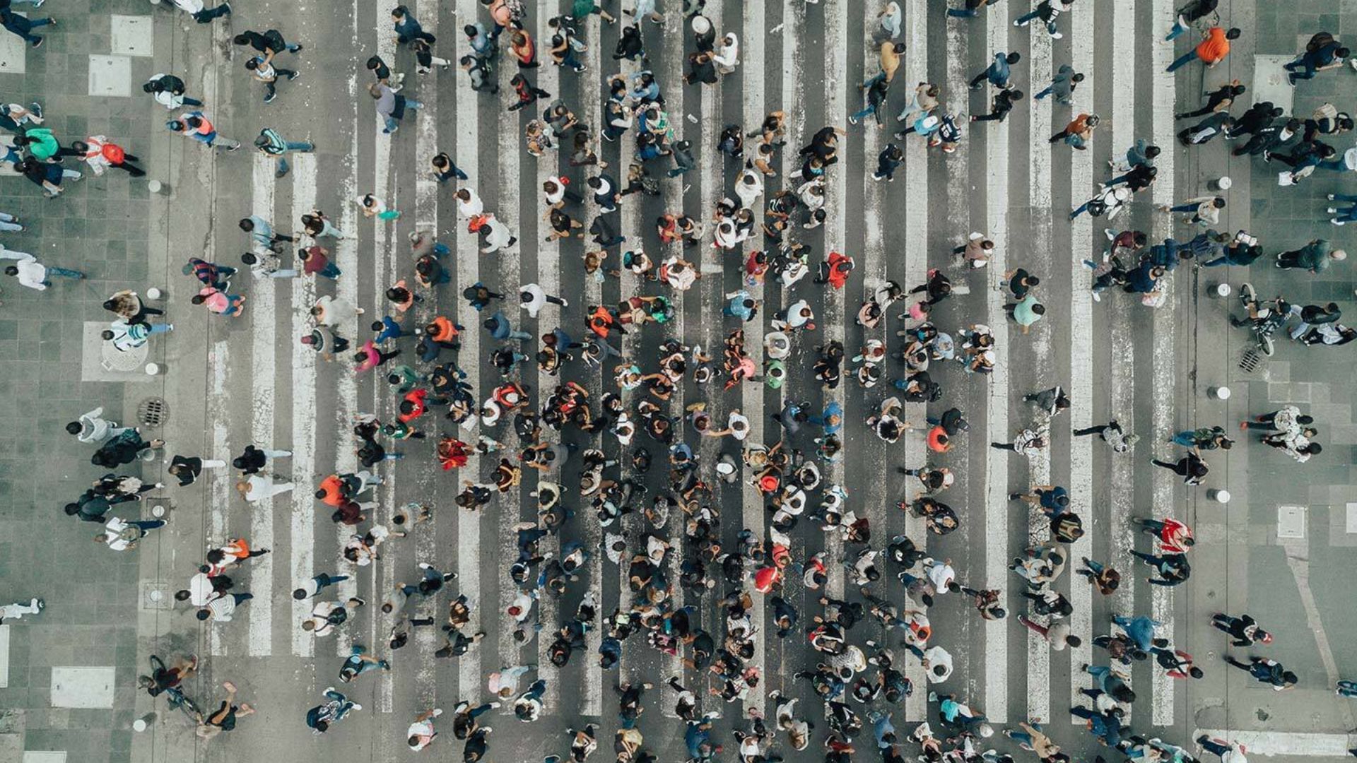 Bir yolun karşı tarafına geçen çok sayıda insanın havadan çekilmiş fotoğrafı.