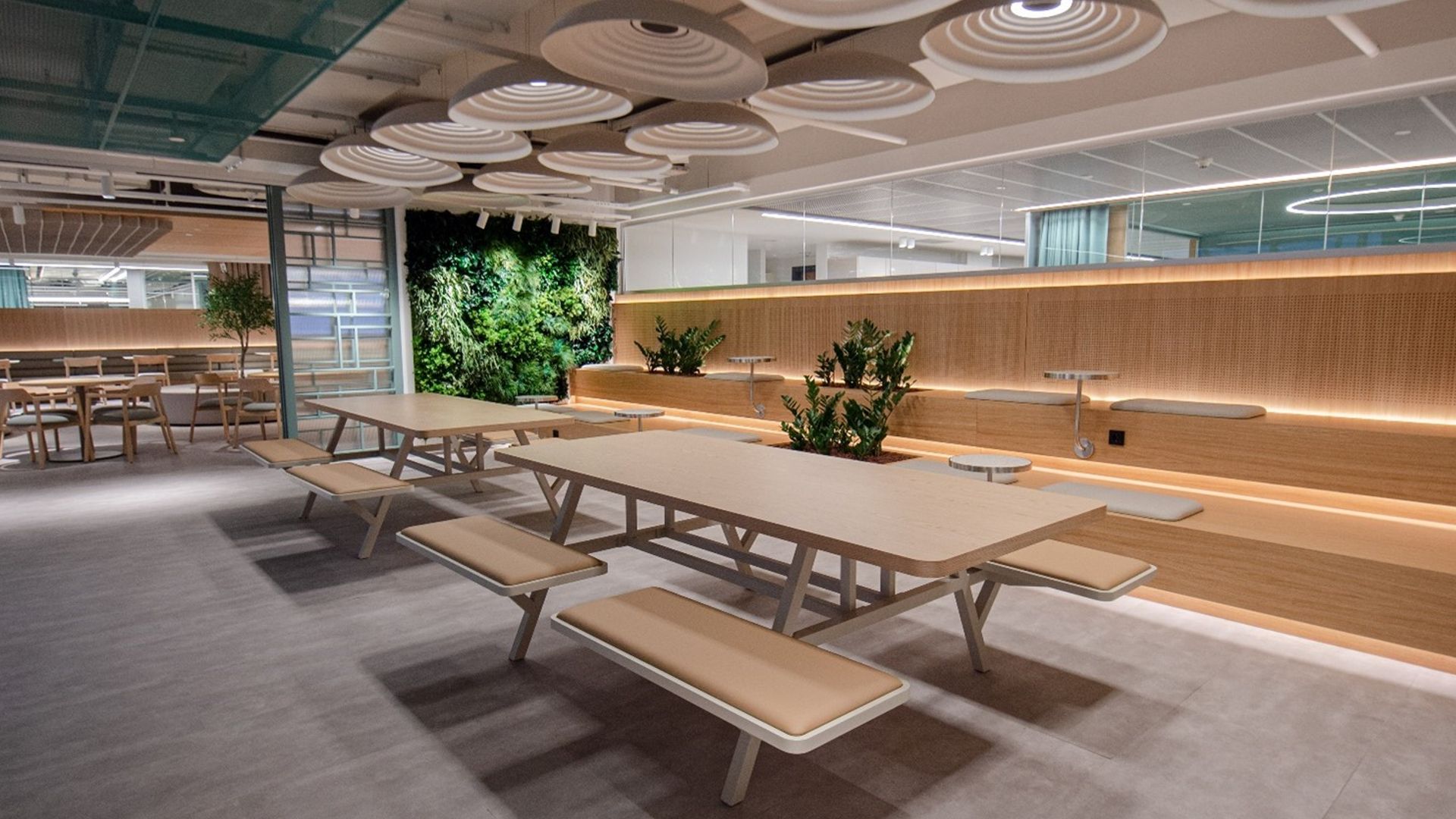 İkinci resimde, duvarda yeşil sarmaşıkların ve ortada da iki adet benchin yer aldığı modern bir oturma alanı yer almaktadır.