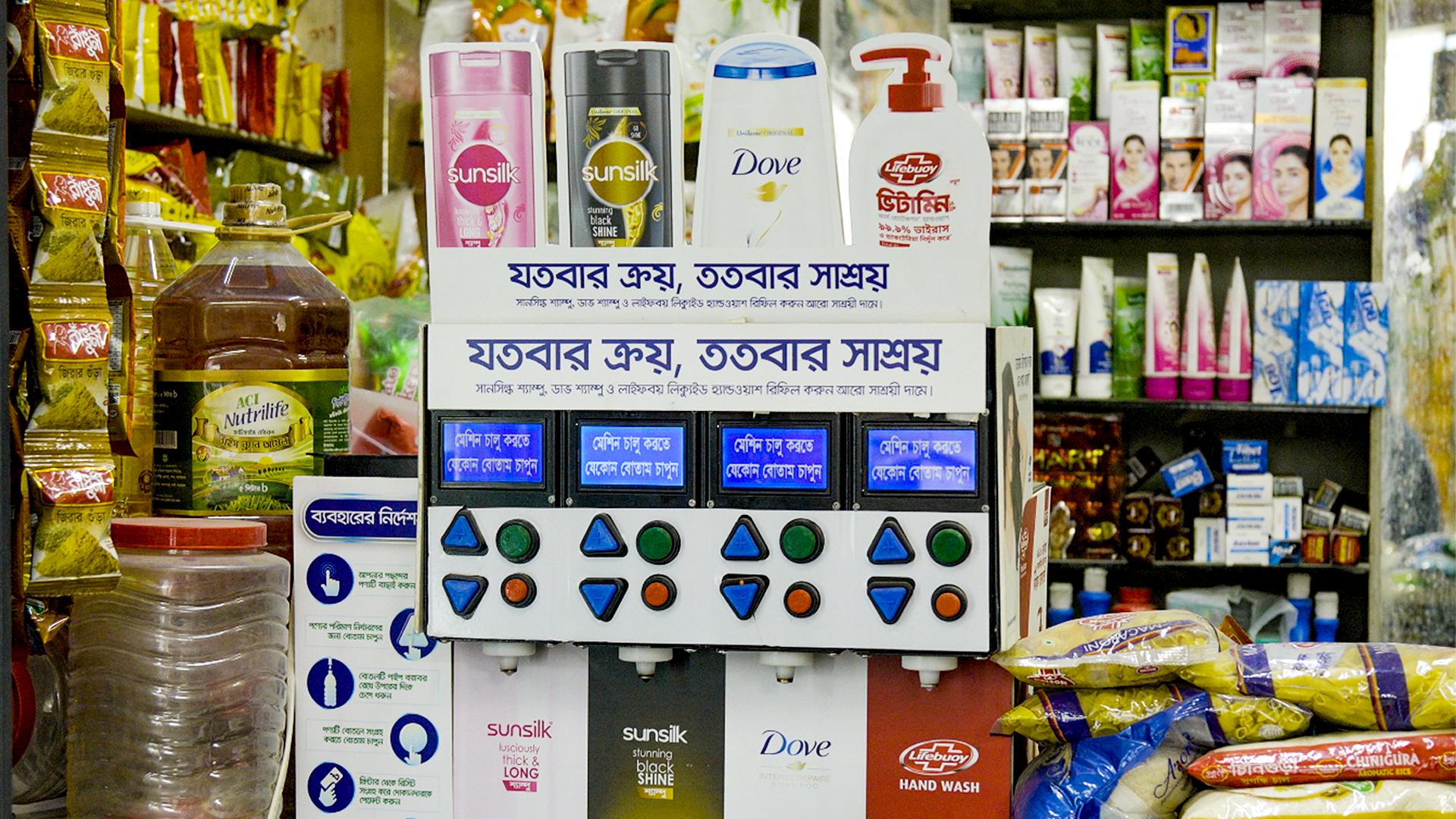 Bangladeş'te küçük bir mağazada kalabalık bir tezgâhta duran, Dove, Lifebuoy ve Sunsilk satan bir Unilever yeniden doldurma makinesi