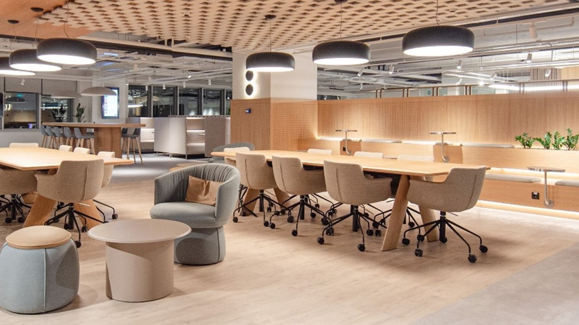 Üçüncü resimde, birden fazla masa ve sandalyenin yer aldığı geniş bir çalışma alanı ile beraber modern avizeler vardır. 