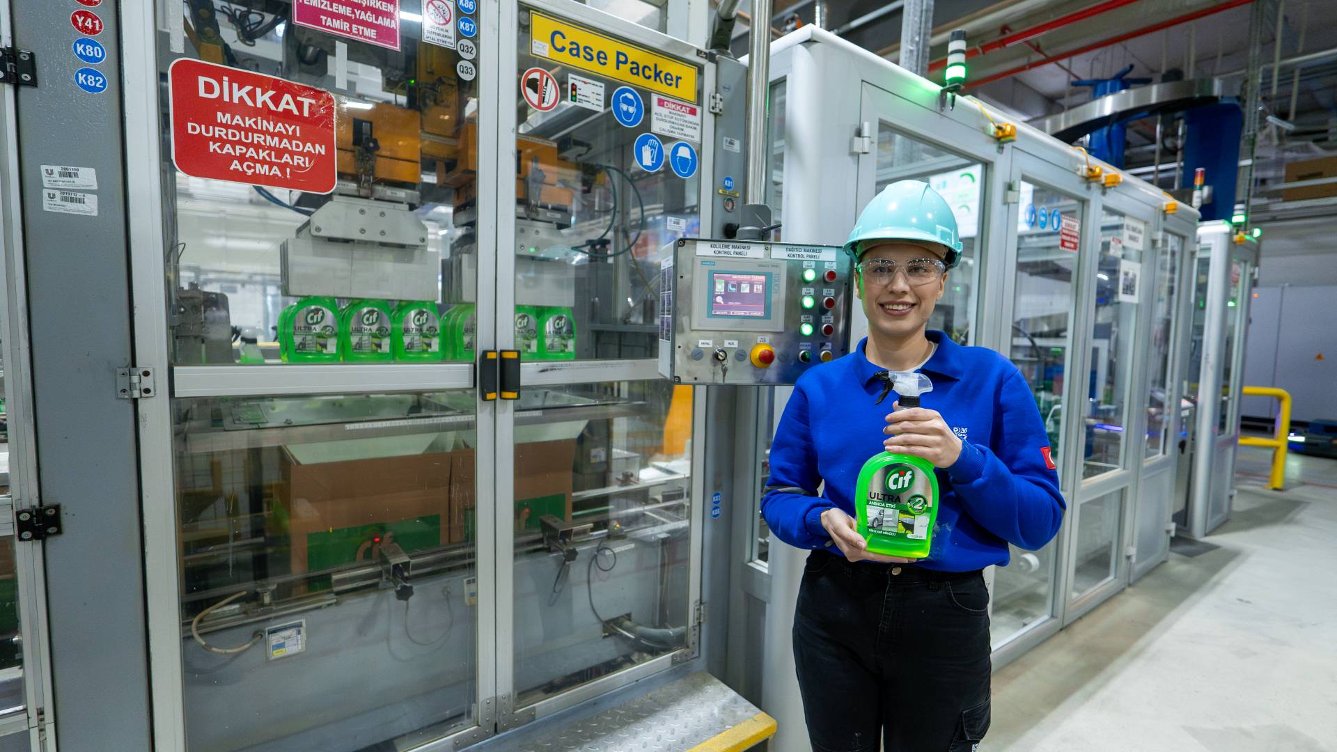 Kadın fabrika çalışan elinde Cif ürünü ile gülümsüyor.