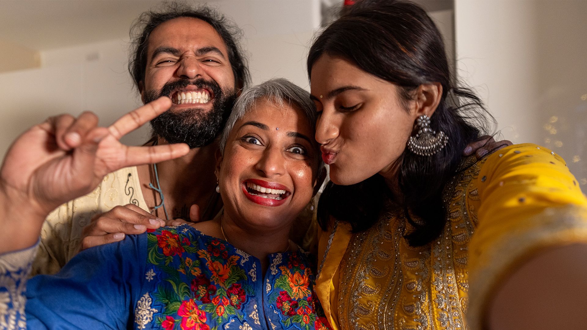 Aynı aileden üç kişi gülümsüyor.